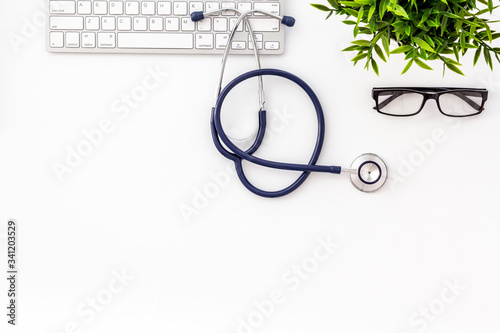 Stethoscope on doctor office desk. White background from above copy space