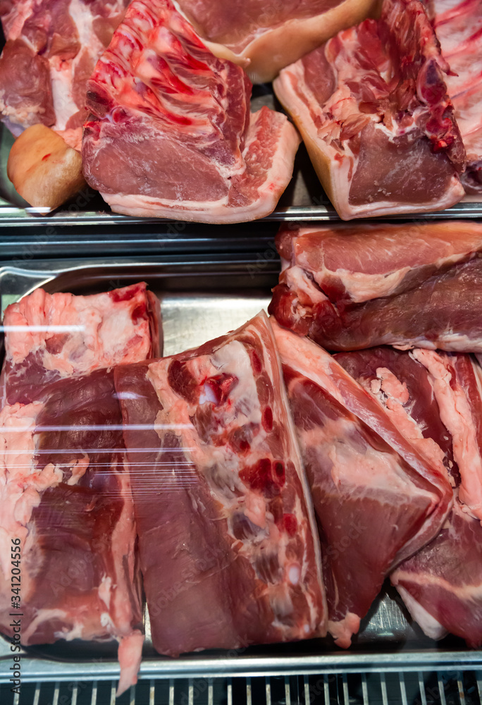 Fresh slices of raw pork meat on counter in supermarket