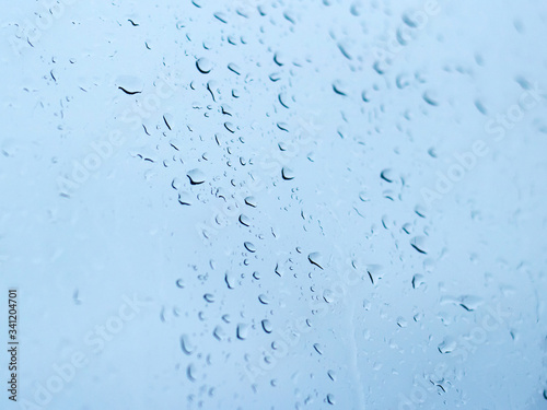 Raindrops on the window glass against the blue sky closeup.