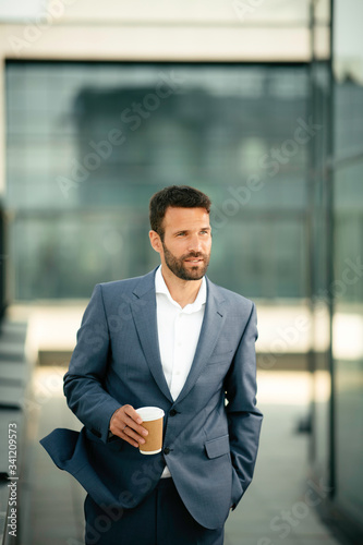 Young businessman in city.. Handsome man drinking coffee outdoors. 