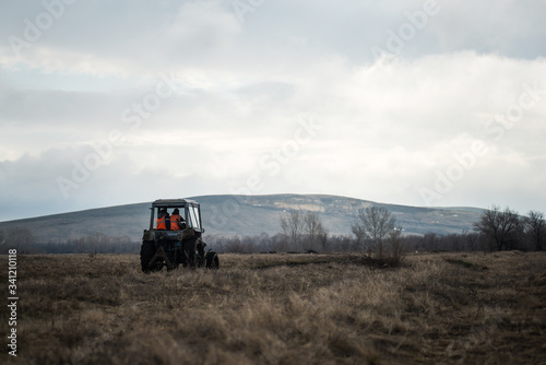 tractor with workers rides on the field in cloudy weather