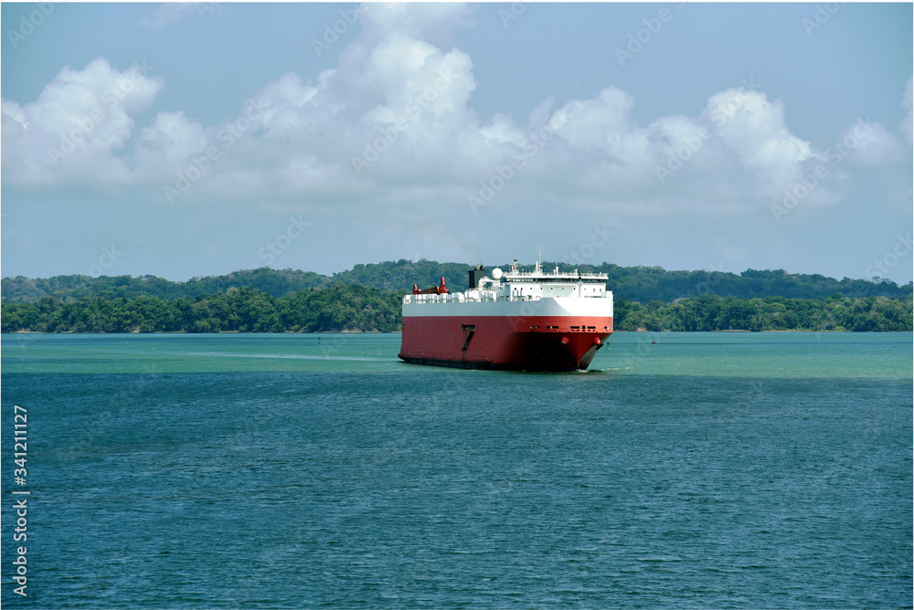 Landscape of the Panama Canal with car carrier ship sailing through Gatun Lake, on her international trade route. 