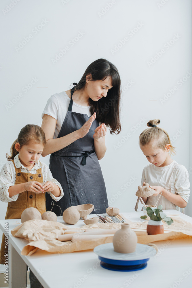 Instructor telling children how to mold clay with their hands Instructor telling children how to mold clay with their hands