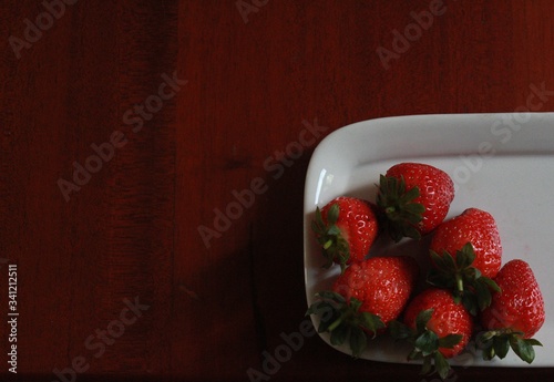 srawberries on a white plate placed in a wooden table with copy space photo