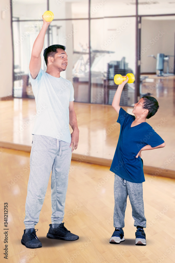 Little son and his father lifting barbell together Little son and his father lifting barbell together