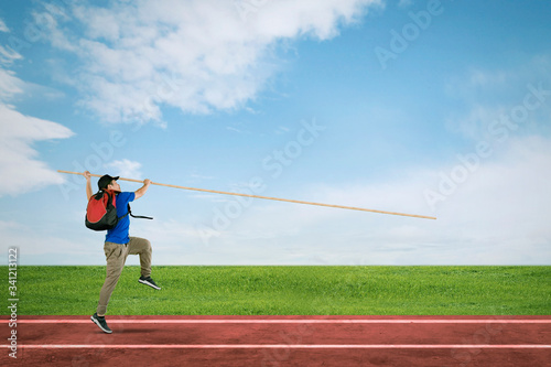 Male student doing pole vault at field