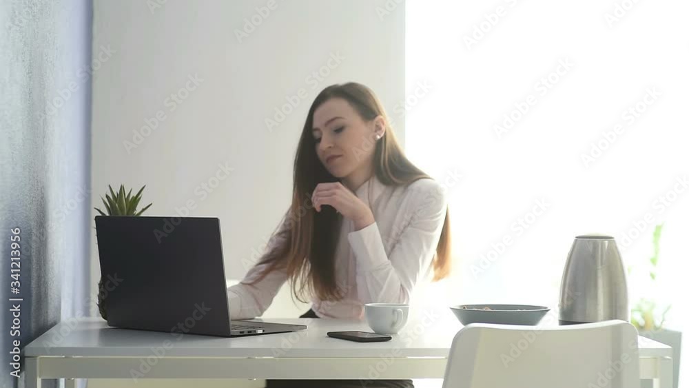 Beautiful happy smiling young designer woman sitting at home office desk with cup of tea, working on laptop and talking phone. Beautiful happy smiling young designer woman sitting at home office desk with cup of tea, working on laptop and talking phone.