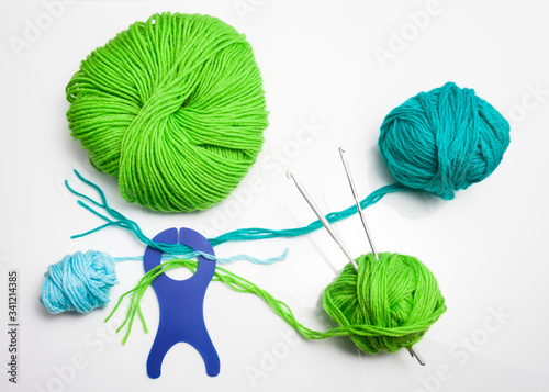 top view of colored yarn balls and knitting needles on white