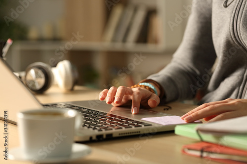 Student hands using touchpad on laptop at night