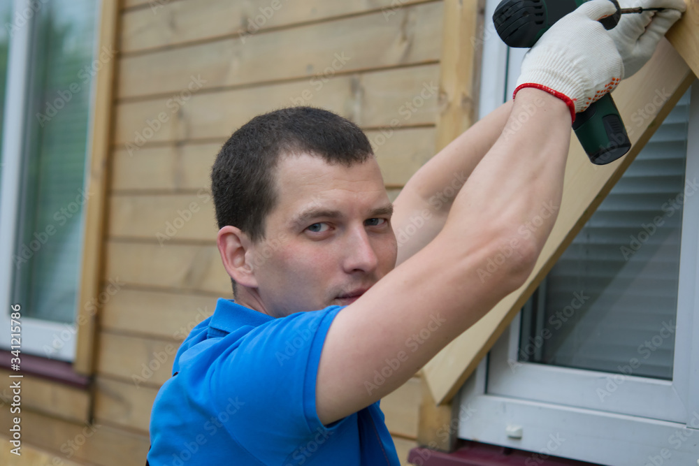 Fototapeta premium a worker in a blue uniform, drills the Windows of the house from thieves when moving to another address