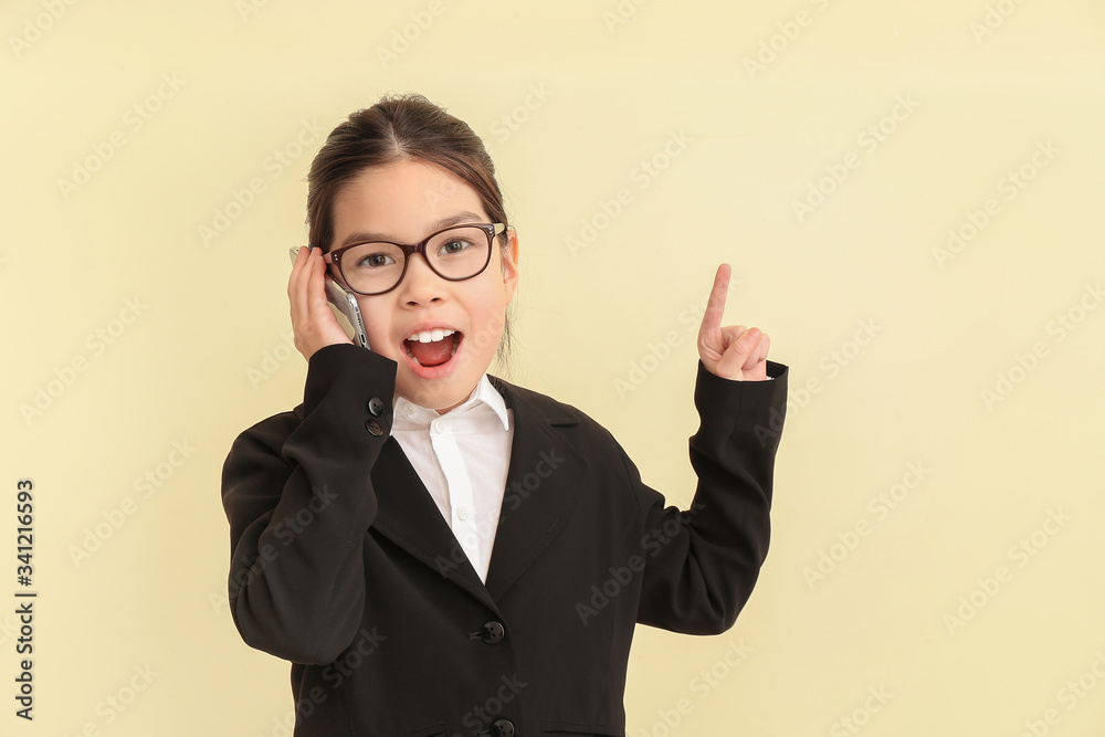 Cute little businesswoman talking by mobile phone on color background Cute little businesswoman talking by mobile phone on color background