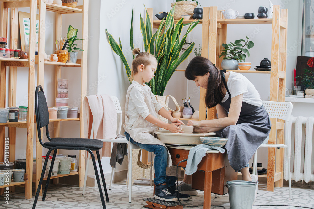 Woman and a boy shaping clay bowl on a pottery wheel in a private workshop Woman and a boy shaping clay bowl on a pottery wheel in a private workshop
