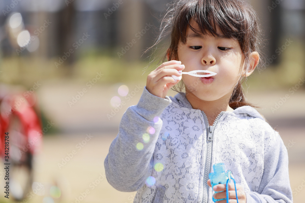 シャボン玉で遊ぶ幼児(5歳児)と青空