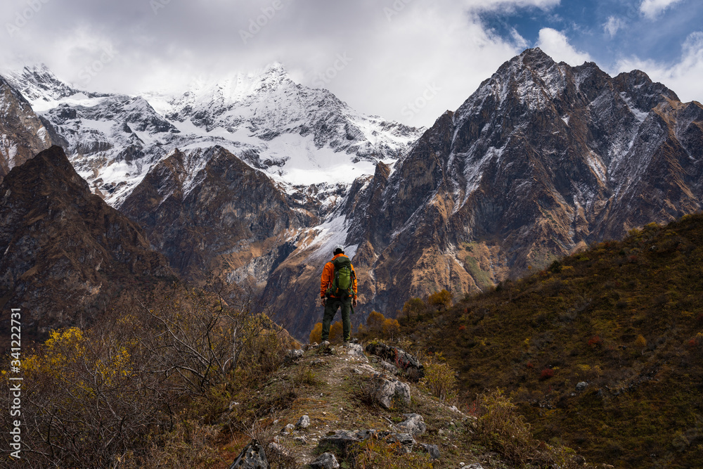 A trekker standing on top of the hill and looking to snow Himalaya mountains range in Manaslu circuit trekking route, Nepal
