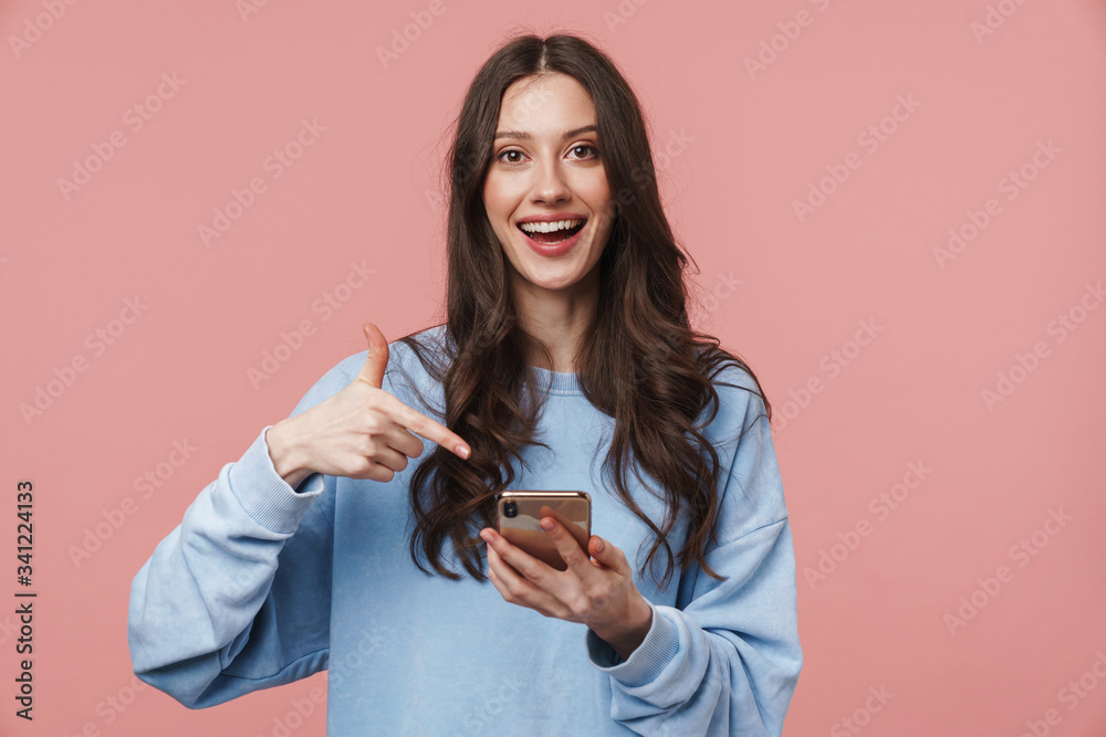 © Drobot Dean - Image of excited young woman using and pointing finger at cellphone
