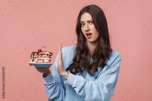 Image of displeased woman doing refusal gesture while holding cake