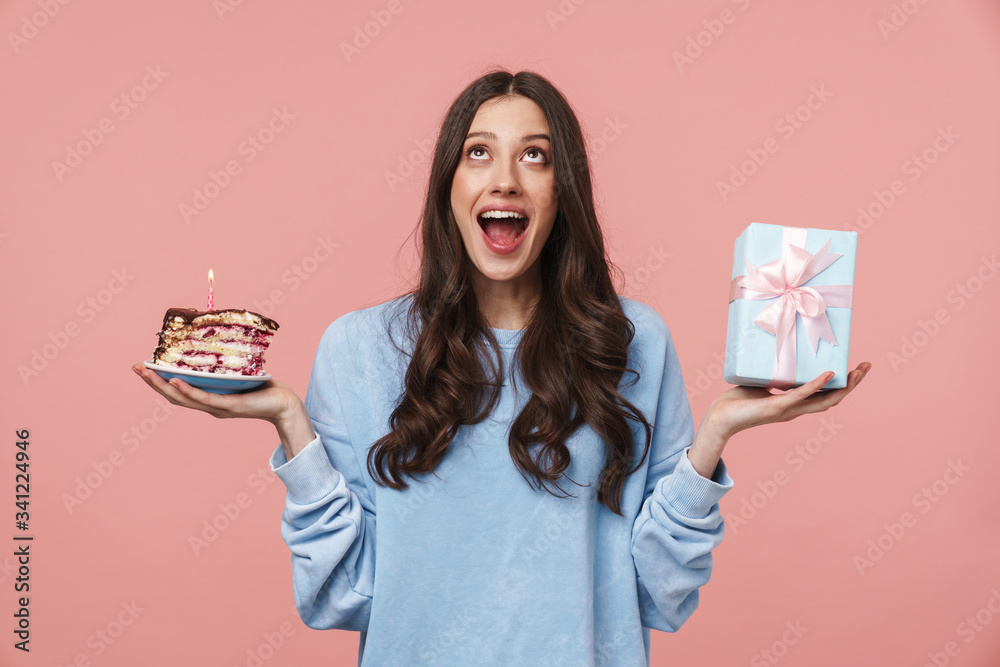 Image of delighted young woman holding birthday cake and present box Image of delighted young woman holding birthday cake and present box