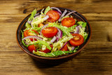 Healthy salad with savoy cabbage, cherry tomato, red onion and olive oil on wooden table