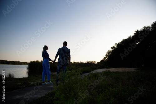 Young couple walks and enjoys the evening sun near the rive.