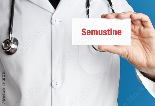 Semustine. Doctor in smock holds up business card. The term Semustine is in the sign. Symbol of disease, health, medicine photo