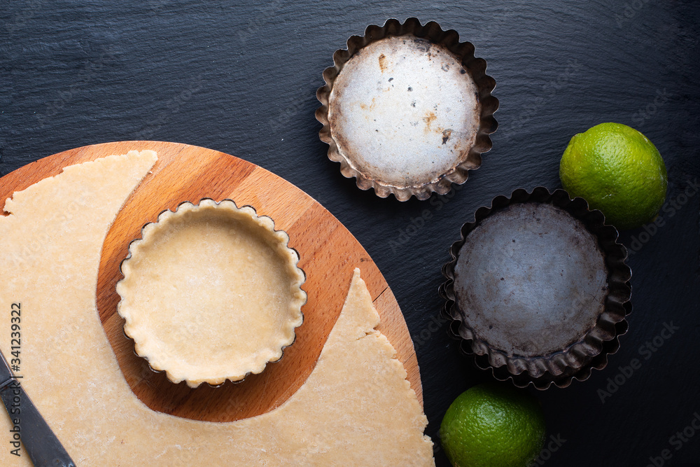 Food concept Homemade emty pie crust for organic Lemon, lime tarts or mini pie on black slate stone board Food concept Homemade emty pie crust for organic Lemon, lime tarts or mini pie on black slate stone board