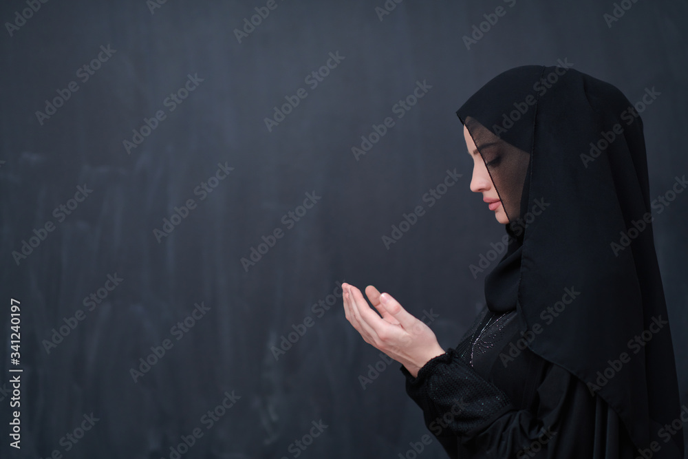 muslim woman making traditional prayer to God in front of black chalkboard