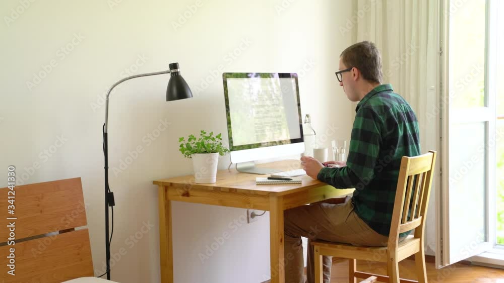Medium shot of man eating granola while working from home, reading a text.