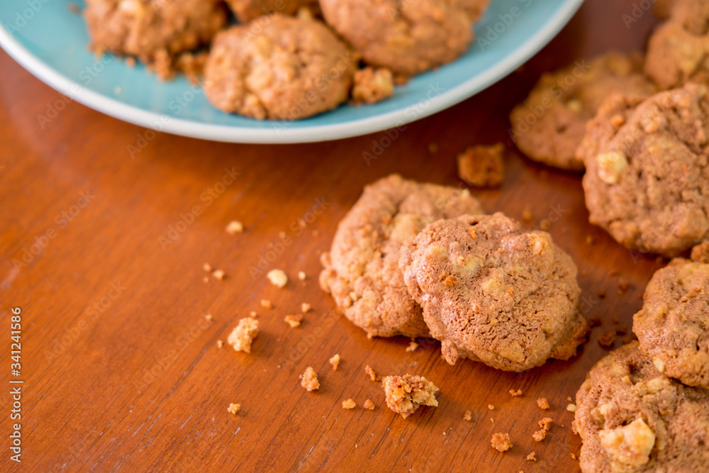 Delicious crunchy homemade chocolate cookies with walnut chunk on top of wooden table and white background. Delicious crunchy homemade chocolate cookies with walnut chunk on top of wooden table and white background.
