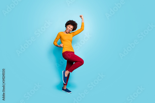 Fototapeta Naklejka Na Ścianę i Meble -  Full length photo of delighted cheerful afro american girl win lottery sales raise fists scream yes hooray wear good look clothing jumper isolated over blue color background