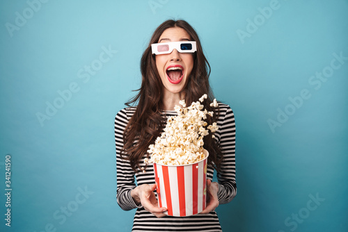 Photo of excited young woman eating popcorn while watching movie photo