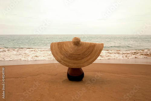 Young beautiful woman on the beach in a big hat