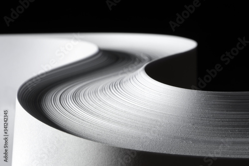 Multiple sheets of rolled A4 paper stack (S-shaped ream) on a black background. Simple, isolated object  with copy space perfect for illustrating various concepts/ideas. Selective focus (shallow DOF). photo