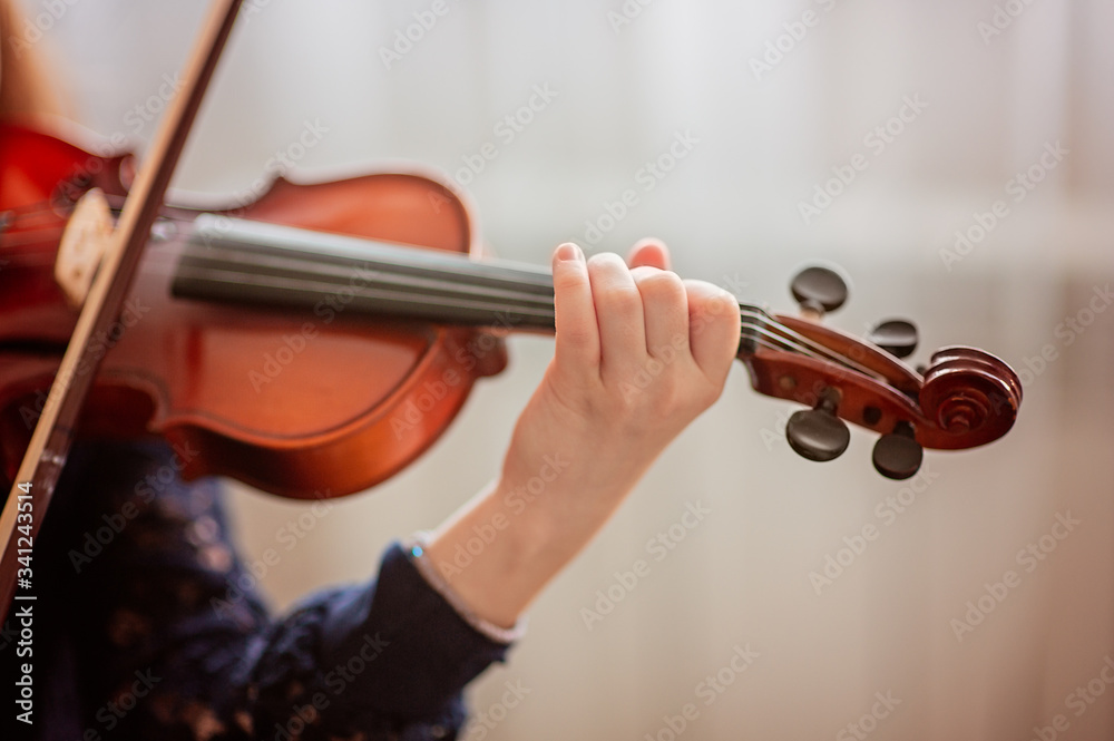 Home lesson for a girl playing the violin. The idea of activities for children during quarantine. Music concept Home lesson for a girl playing the violin. The idea of activities for children during quarantine. Music concept