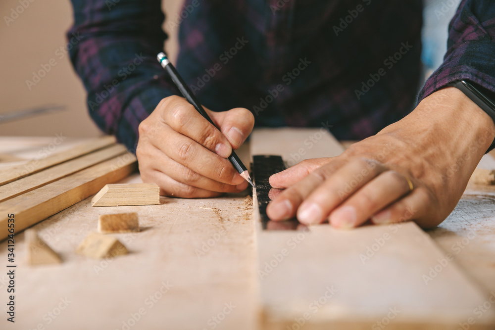 carpenter with a pencil and ruler mark on wooden board on table. Construction industry, housework do it yourself.