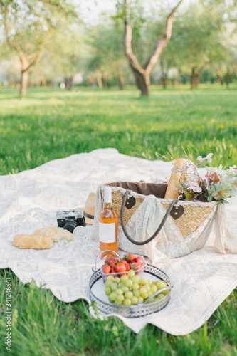 picnic in the park with beautiful food: strawberries, grapes, croissants, a bottle of wine with two glasses