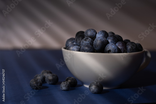 Cup of fresh blueberry fruit in dark and moody lighting
