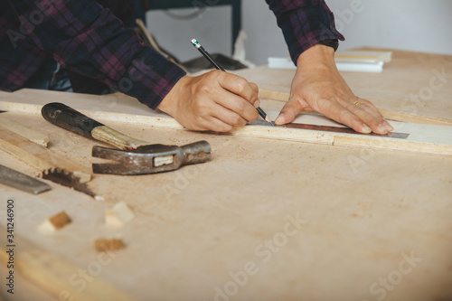 carpenter with a pencil and ruler mark on wooden board on table. Construction industry, housework do it yourself.