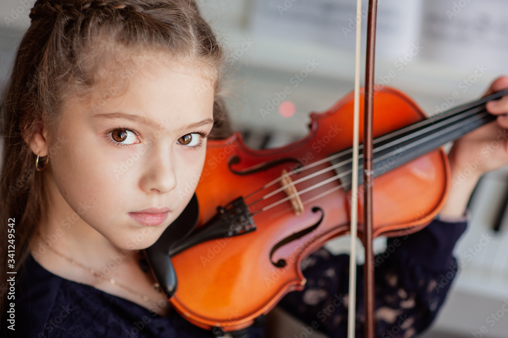 Home lesson for a girl playing the violin. The idea of activities for children during quarantine. Music concept Home lesson for a girl playing the violin. The idea of activities for children during quarantine. Music concept