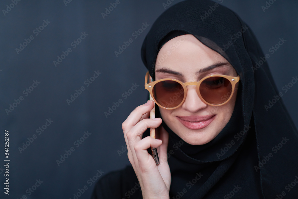 young muslim woman wearing sunglasses using smartphone young muslim woman wearing sunglasses using smartphone