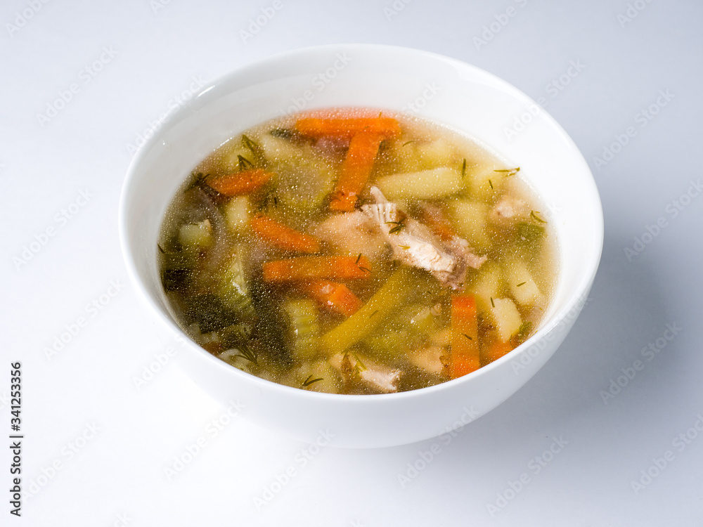 Chicken soup in a white bowl on a white background. Side view