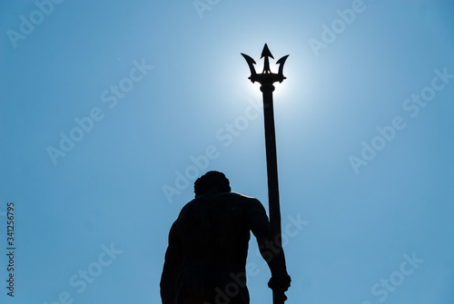 Neptune statue with trident covering the sun