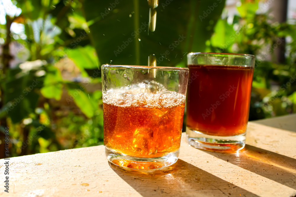 Outdoor Tea pouring into glass cup transparent with day sunlight.
Outdoor Tea pouring into glass cup transparent with day sunlight.