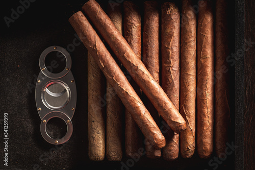 Tableau sur toile Top view of cigars with metal cutter in humidor