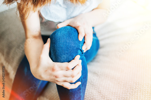 girl sitting on bed clutching a sore knee