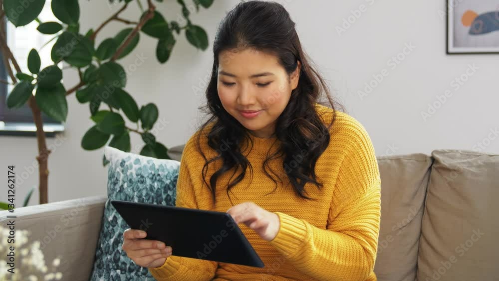 internet banking, online shopping and technology concept - happy young asian woman sitting on sofa with tablet pc computer and credit card at home internet banking, online shopping and technology concept - happy young asian woman sitting on sofa with tablet pc computer and credit card at home