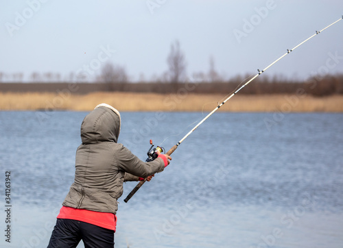The girl catches fish in the lake for fishing rod.
