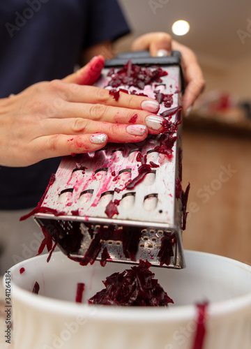 Girl cuts boiled red beets on a grater