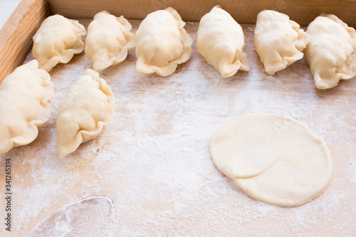 National Russian cuisine. Pierogi or pyrohy, vareniki, served with cottage cheese and potatoes on board. Raw dumplings made of dough in handmade flour