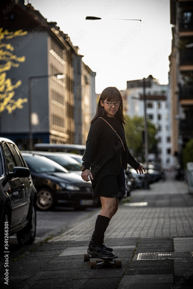 Japanese woman riding skateboard in sidewalk