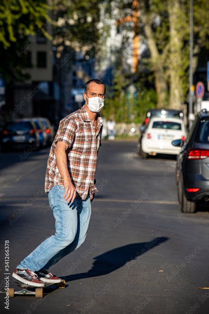 Man skateboarding using face mask in street at sunny day Man skateboarding using face mask in street at sunny day